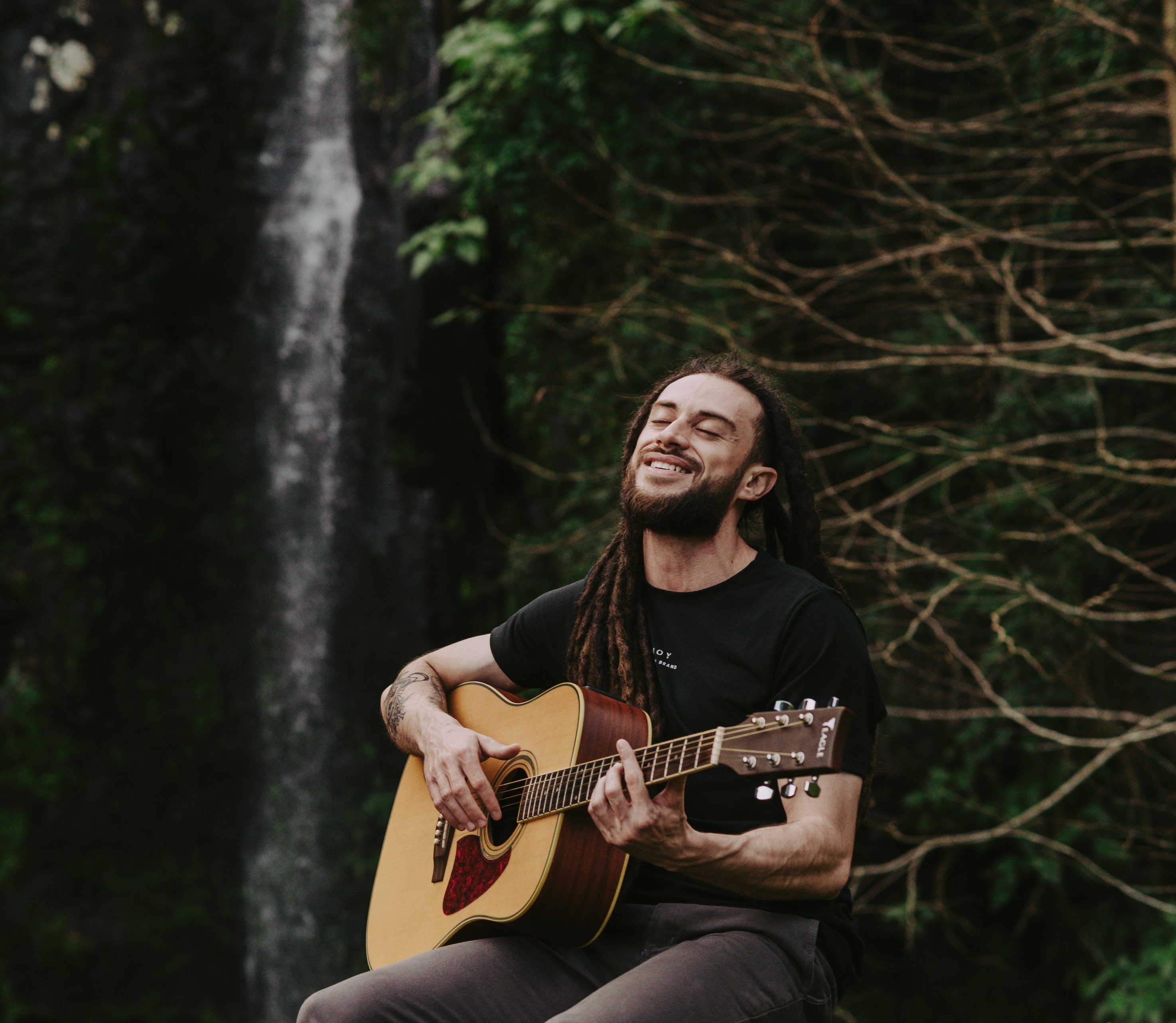 Músico tocando violão à beira de uma fogueira na natureza
